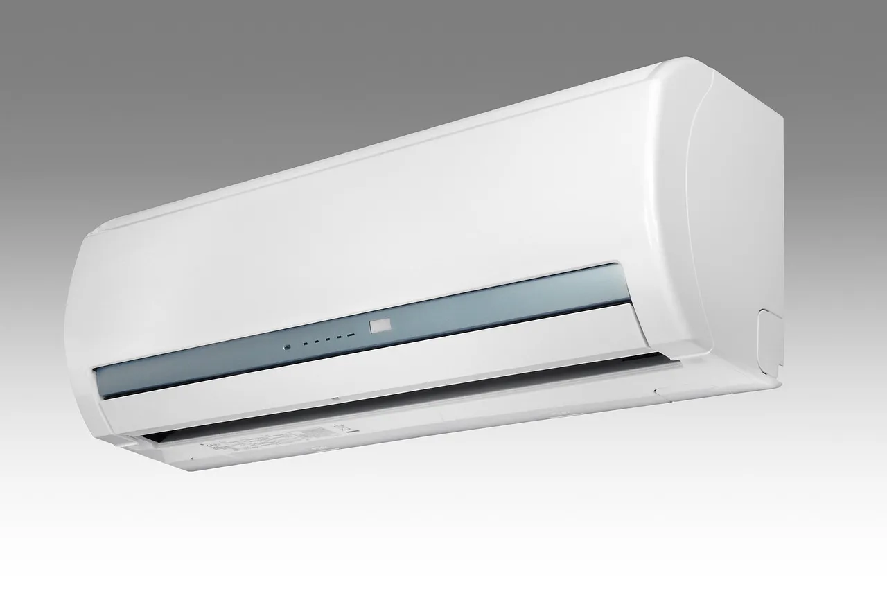 A plain white wall-mounted indoor air conditioner unit seen from slightly below, against a grey background