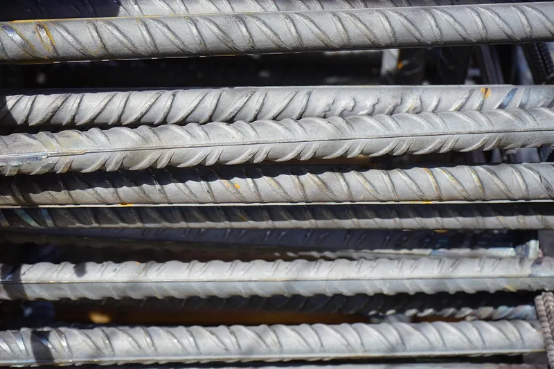 Ribbed steel reinforcing bars lying stacked in sunlight