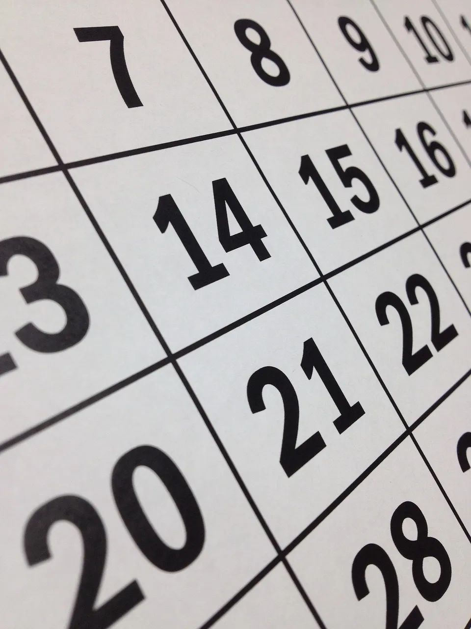 A close, angled view of a printed calendar page: large black day numbers in a ruled grid, with 14, 15, 21 and 22 in the middle.
