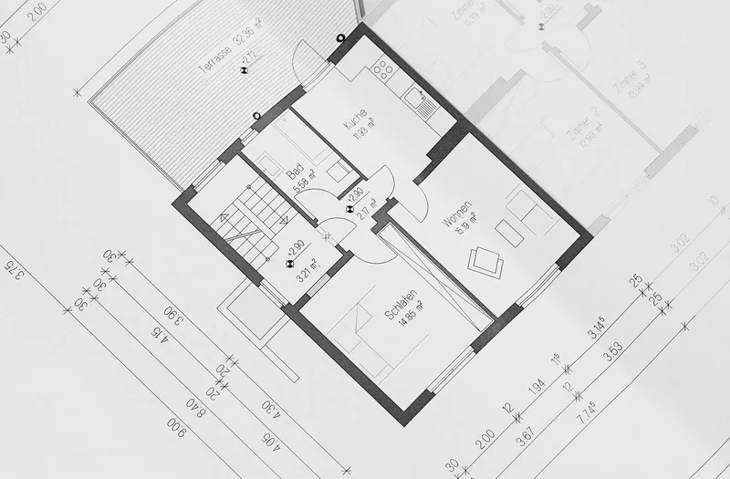 A printed floor plan of a small dwelling, with room areas and dimension lines, photographed at an angle
