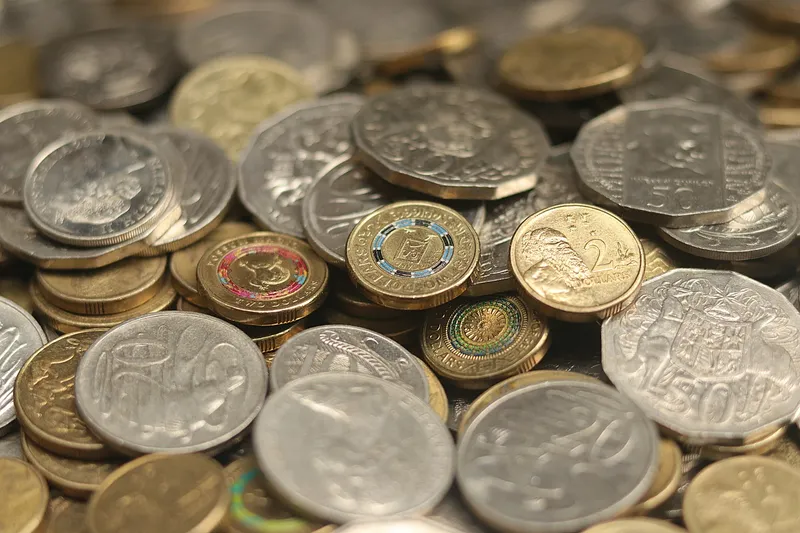 A heap of Australian coins, silver and gold, close up and softly lit