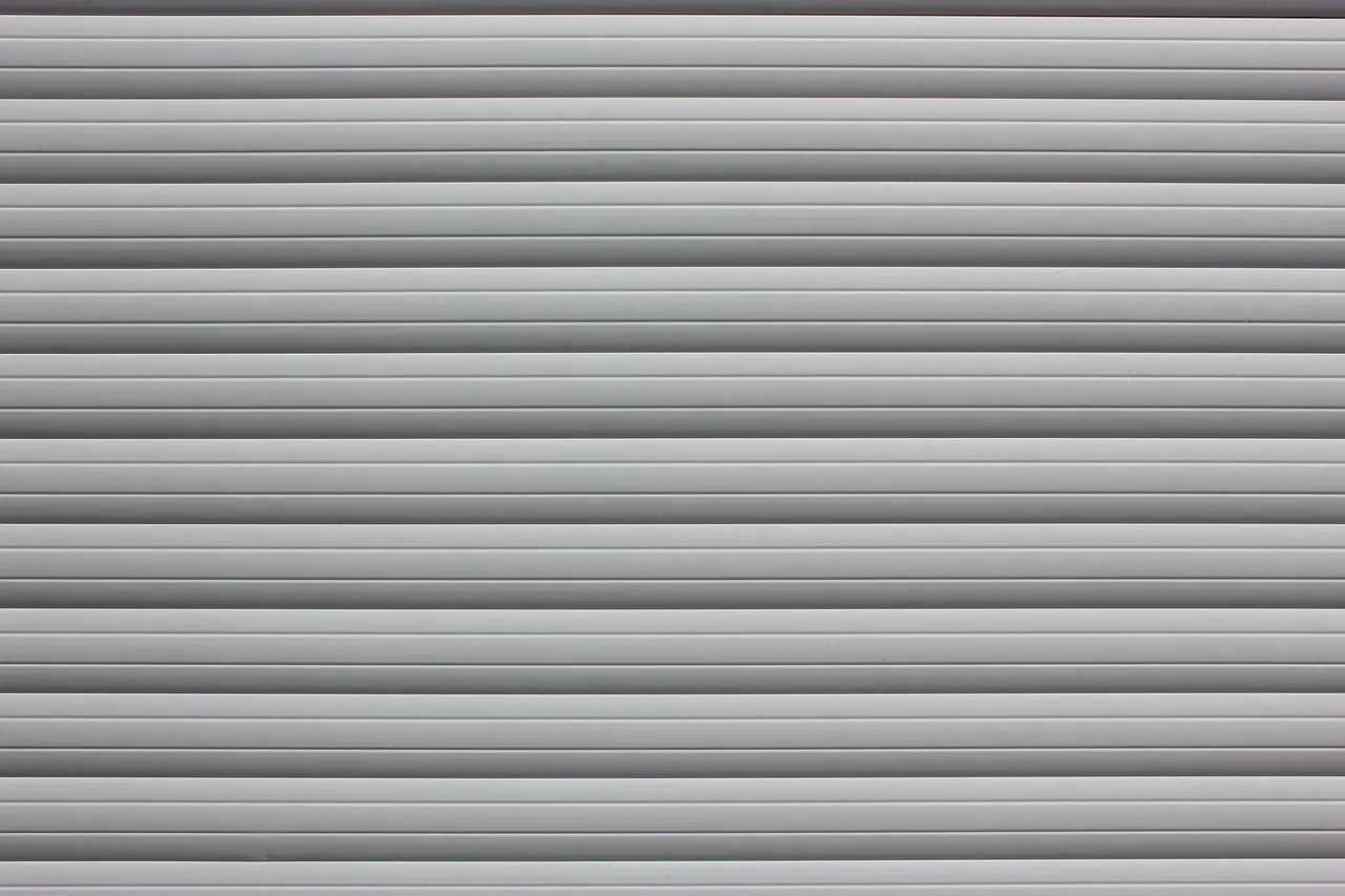 The grey aluminium slats of a closed roller shutter, seen straight on.