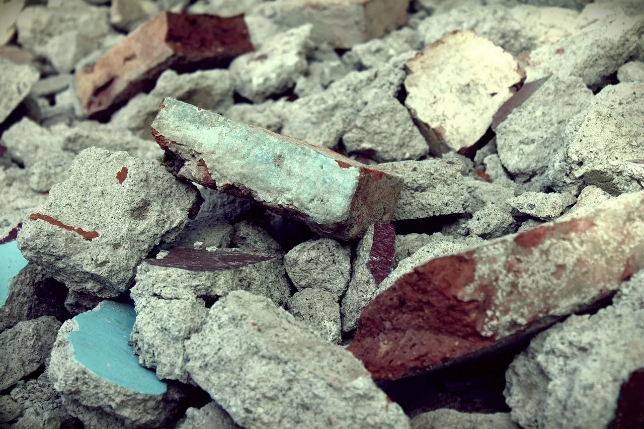 A heap of broken red bricks and grey lumps of concrete, some pieces with painted faces