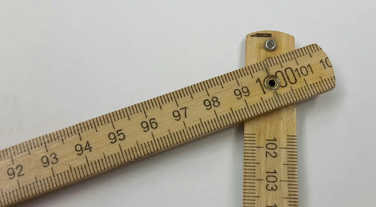Two arms of a wooden folding rule crossing at the 100 centimetre mark, held together by a brass rivet.