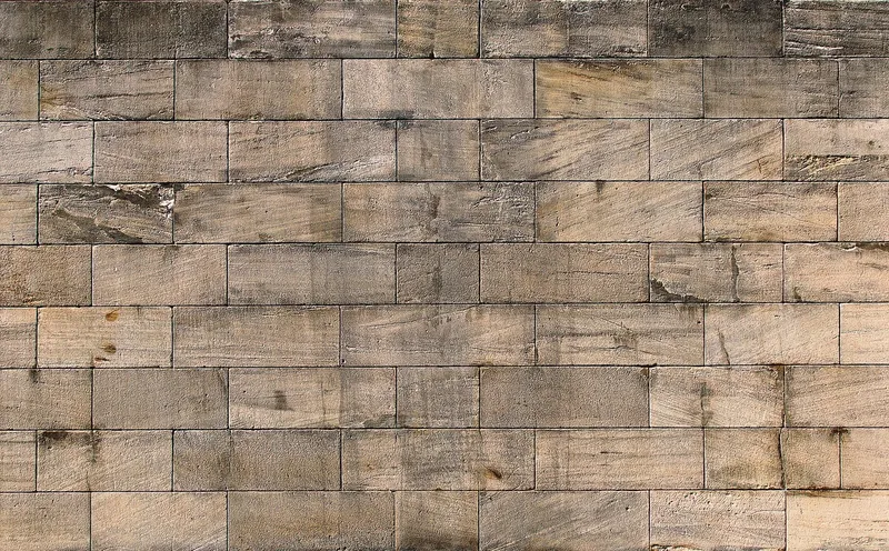 A wall of weathered, dressed sandstone blocks laid in even courses
